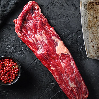Raw hanger steak with knife and ingredients beside