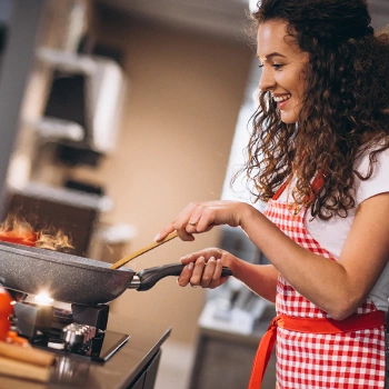 A woman with a checkered apron cooking in the kitchen