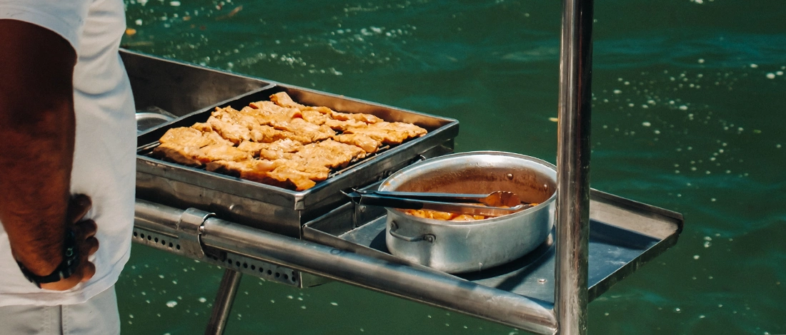 A man cooking on grill inside a boat
