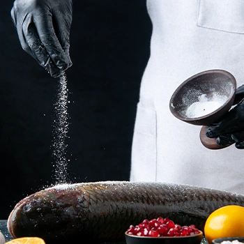 A chef sprinkling salt on fish
