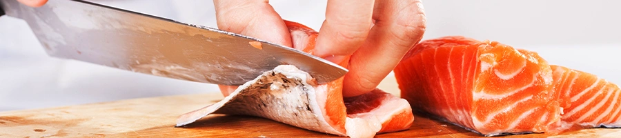 Slicing raw salmon on cutting board