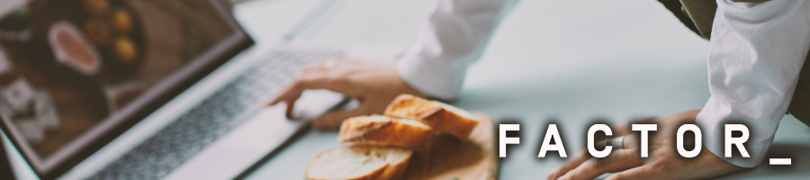 A man looking up things on a laptop with bread beside him