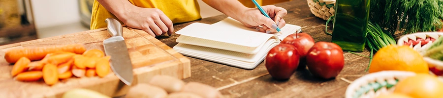 A woman taking notes in the kitchen while cooking