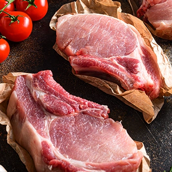 Raw pork chops with tomatoes and paper bags