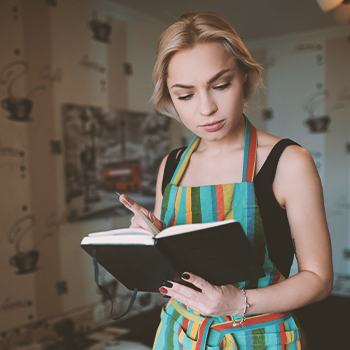 A woman thinking while looking at a cookbook