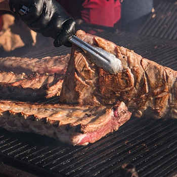 Using a tong to flip a rib meat