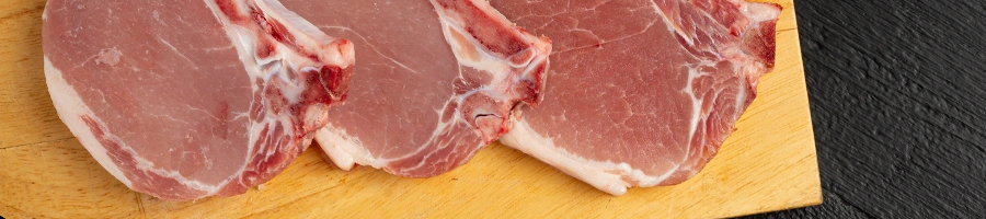 Three kinds of pink pork chops on cutting board