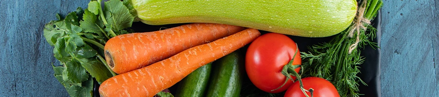 Fresh zucchini, carrot, tomatoes, greens, on black tray plate