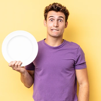 man thinking while holding an empty plate