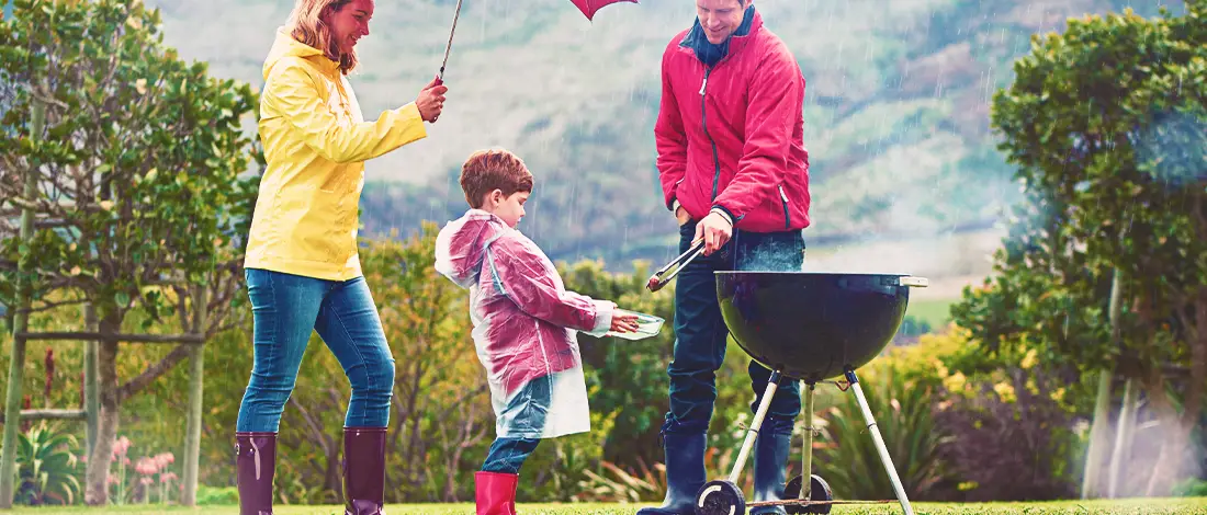 A family barbecuing in the rain