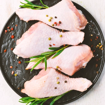 Raw chicken drumsticks on a plate