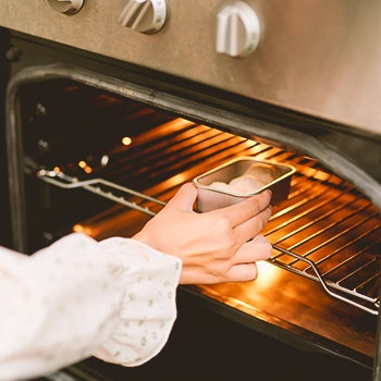 A person putting food inside the oven