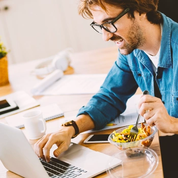 A person eating while using the laptop