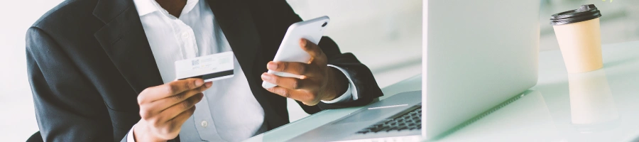 A person looking at his phone in front of a laptop