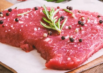 Raw steak with herbs and spices on top