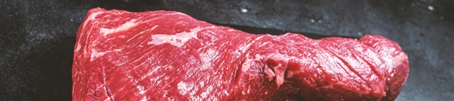 Raw bottom round steak on a black table