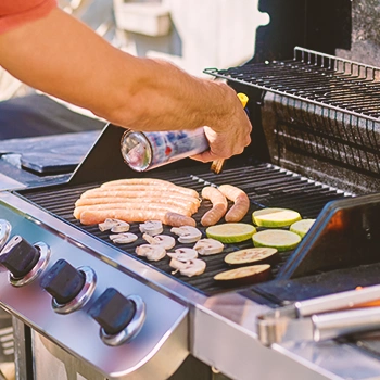 A person spraying oil on a grill