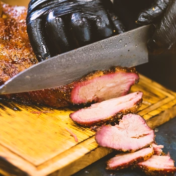 Someone slicing meat on a chopping board