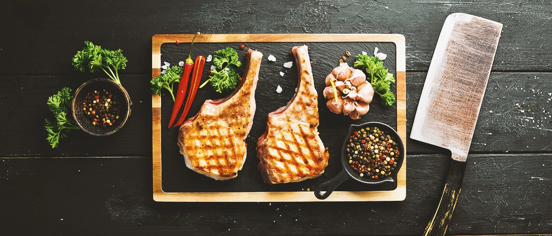 Two steaks on a wooden board with herbs