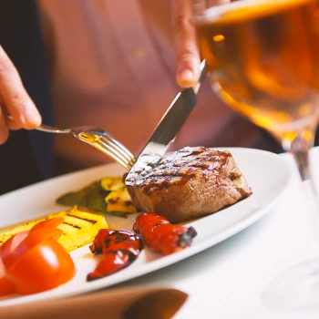 A person eating steak at a restaurant