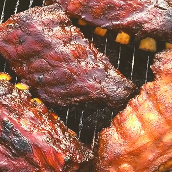 Ribs being cooked and smoked on a grill