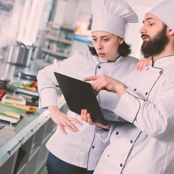 Two chefs looking at a laptop