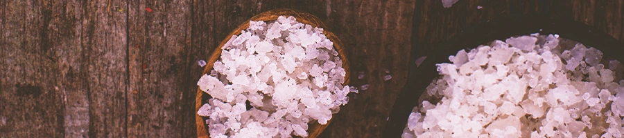Top view shot of salt on a wooden spoon and wooden bowl
