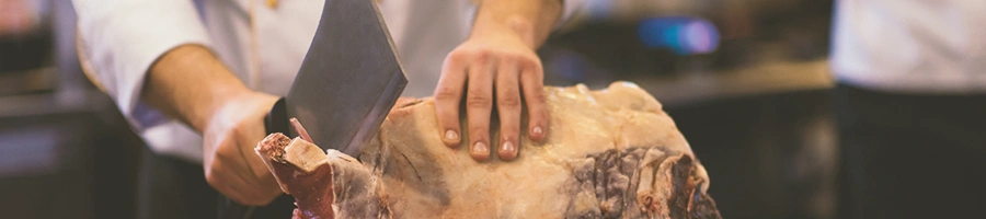 A butcher cutting up raw beef