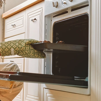 A person putting a tray inside an oven