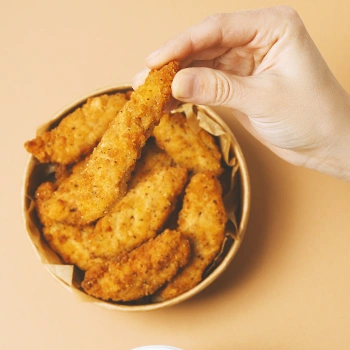 A person taking from a stack of chicken steaks