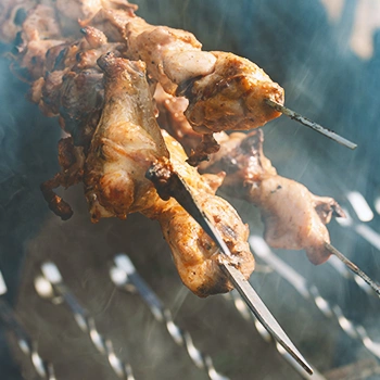 Close up shot of cooked meat above a smoky grill