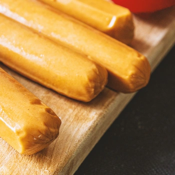 Close up shot of four chicken sausages on a wooden board