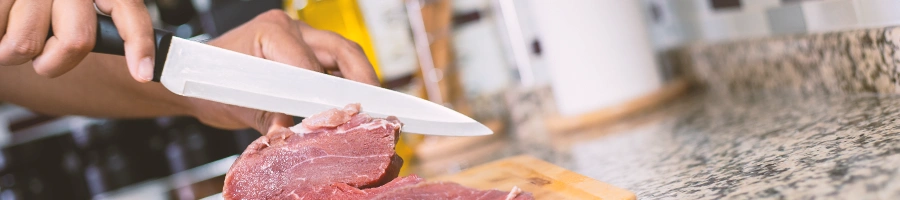 A person slicing steak in a home kitchen