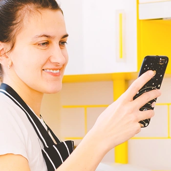 A person looking at her phone in the kitchen