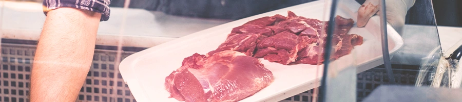 A butcher getting meet from a glass storage