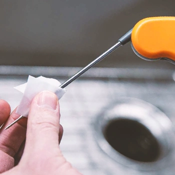 A thermometer probe being cleaned