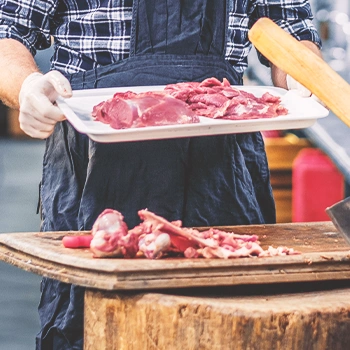 A butcher holding a tray of meat