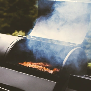 A smoker with food inside and a lot of smoke fuming out