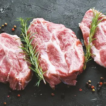 Top view of raw steaks in a row with herbs and spices