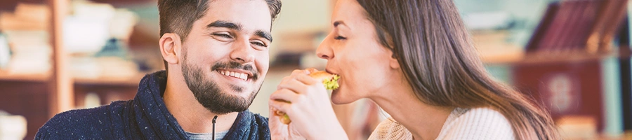 A couple eating a sandwich out in a restaurant