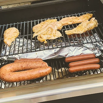 Sausages and meat on grills inside a smoker
