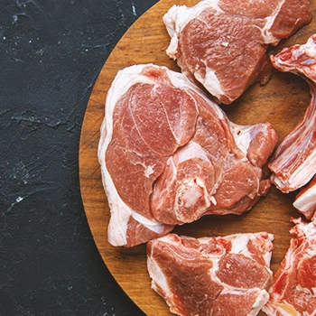 Frozen raw meats on a wooden board on a black table