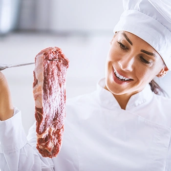 A chef looking at a piece of raw beef