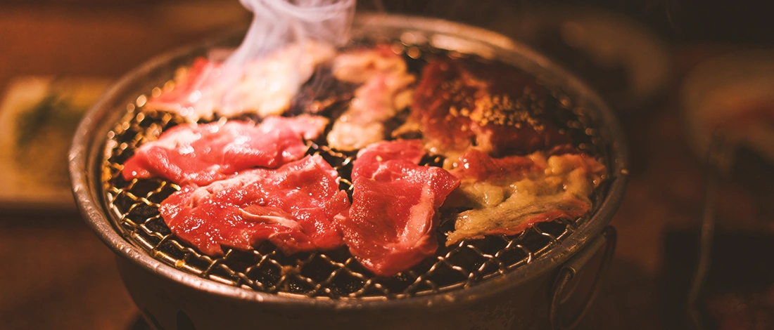 Close up shot of a korean bbq grill with meat being cooked