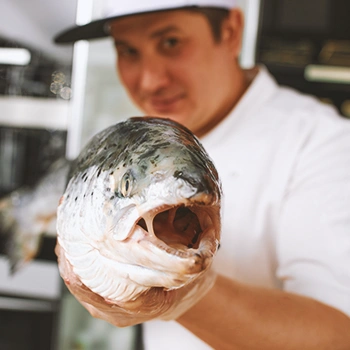 A chef holding a fish to the camera