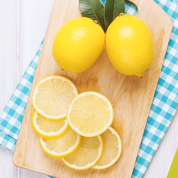 Sliced lemon and whole lemons on a wooden board