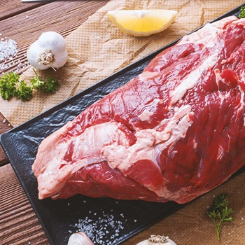 Close up shot of raw beef on a black plate on a wooden table