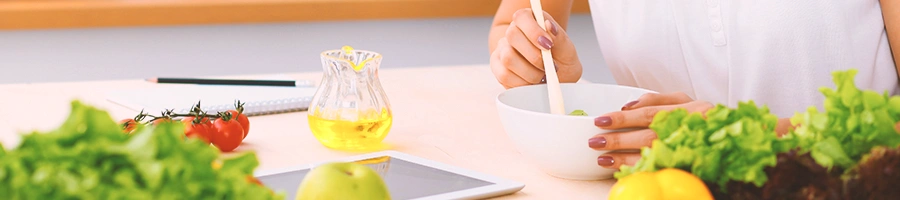 A person mixing a bowl while looking at a tablet in a kitchen