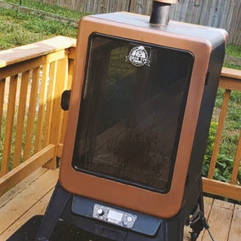 A small vertical smoker in a backyard