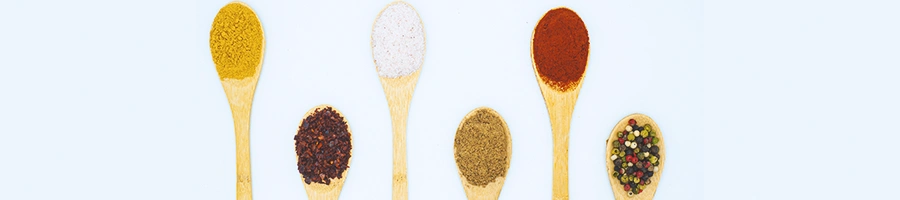 A row of wooden spoons of seasonings